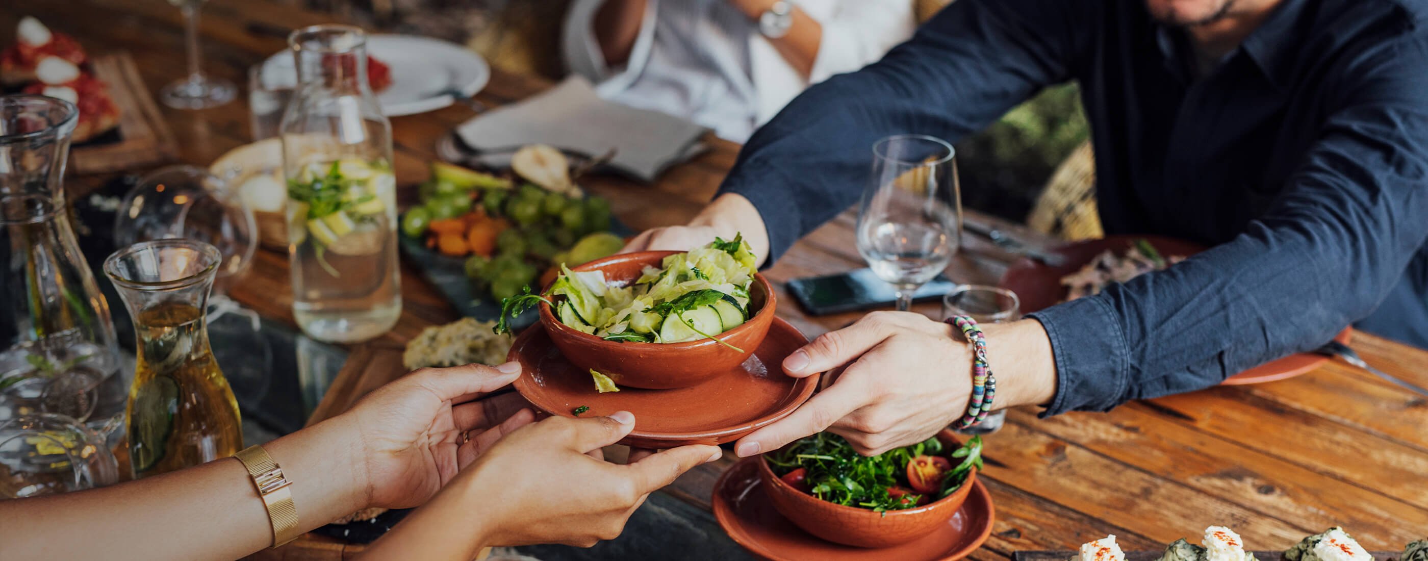 Bowl of fresh food passed across a table